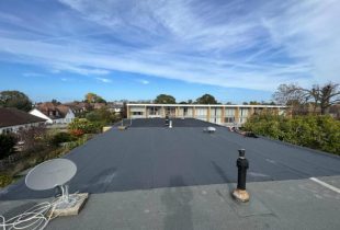 A flat rooftop with small structures including a satellite dish, chimney, and ventilation pipes by 5 Star Roofcare in Staines, Shepperton, Chertsey, and London.